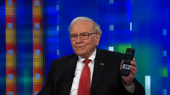 Warren Buffett holding up a flip phone